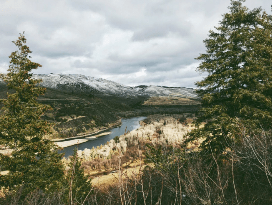 winter film foto van een berglandschap met bomen framing het beeld van besneeuwde bergen en een rivier