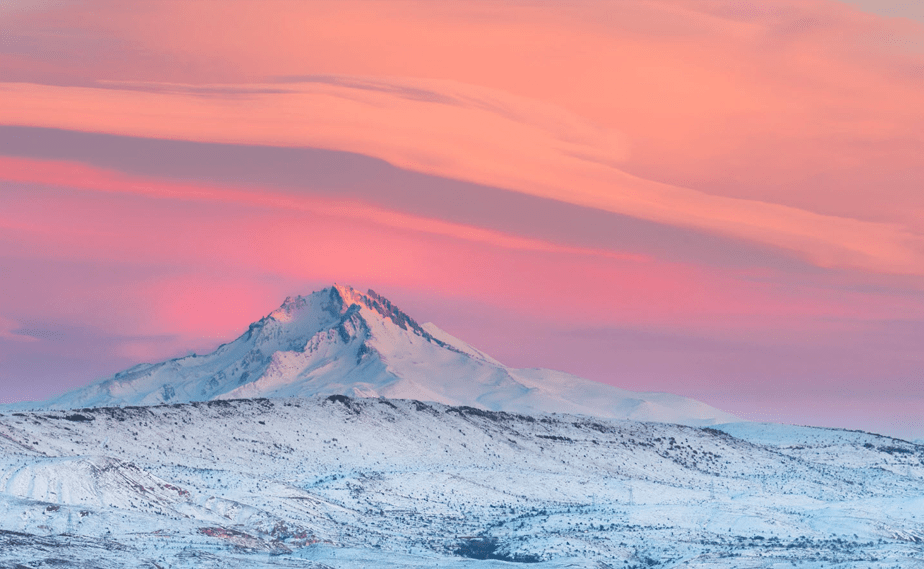 roze en oranje zonsondergang boven een besneeuwde berg